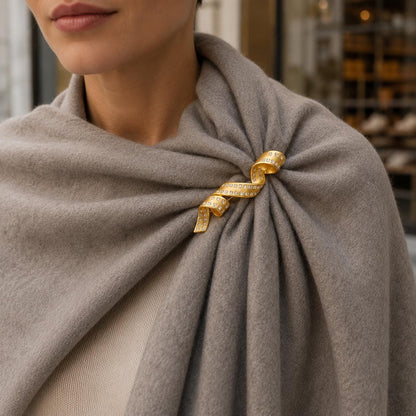 Gold spiral brooch on neutral background