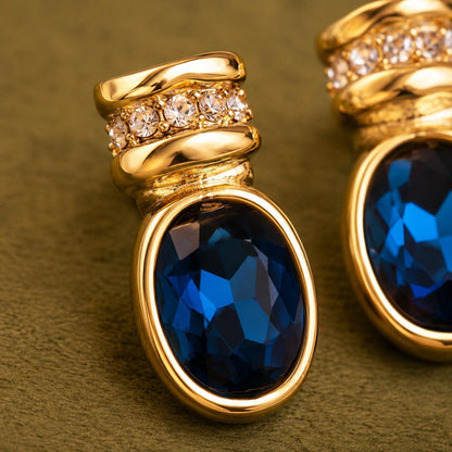 Blue glass gold oval stud earrings on neutral background