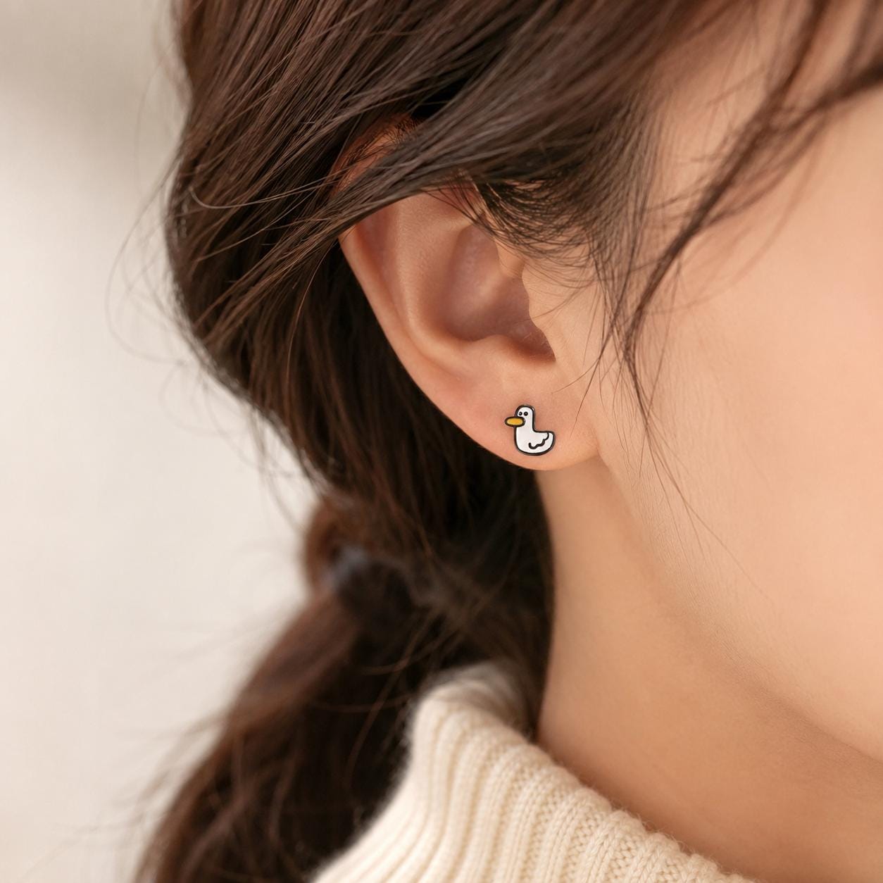 Duck stud earrings on neutral background