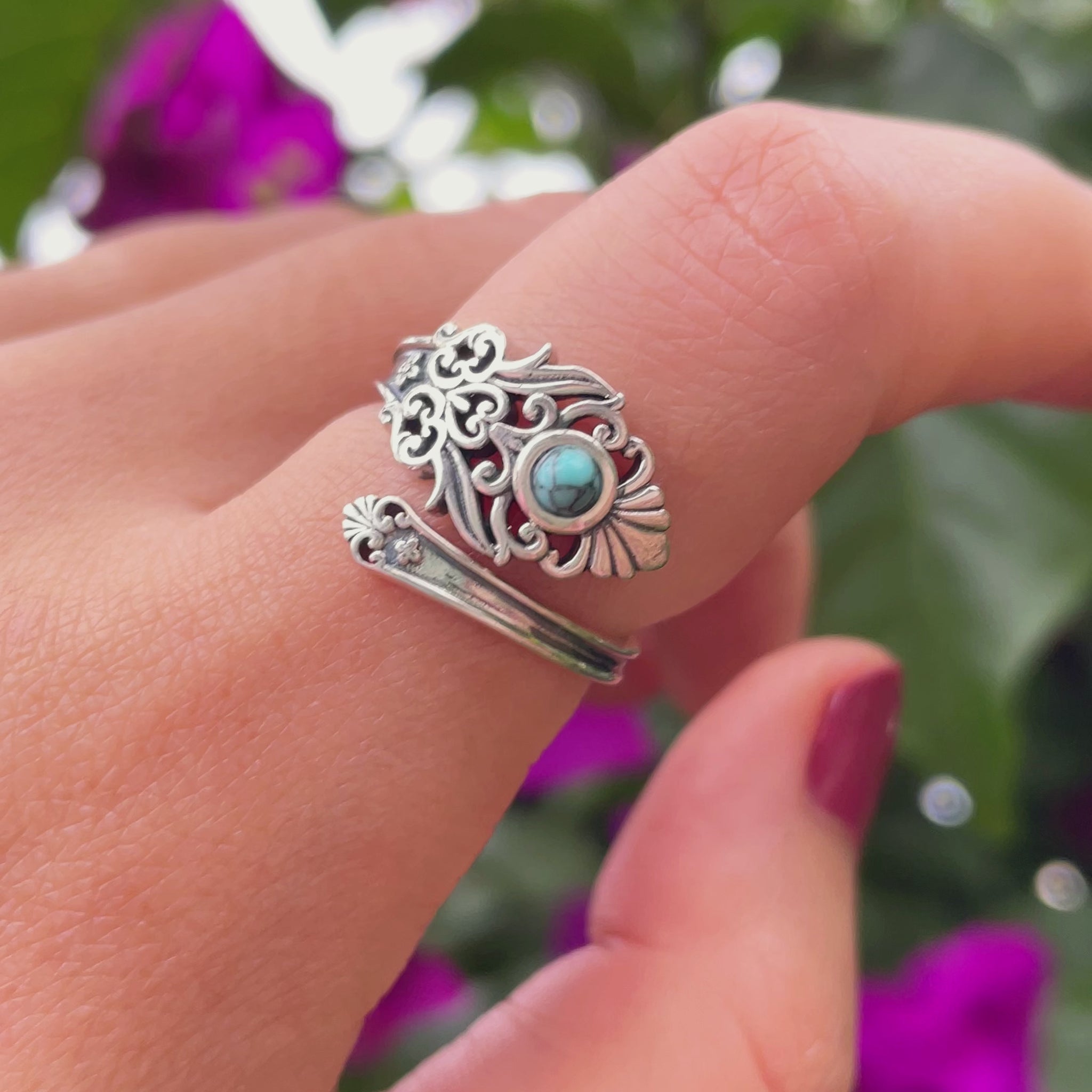 A close-up of a vintage turquoise spoon ring, with a smooth, curved silver band and a teardrop-shaped turquoise stone in the center.