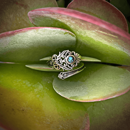 A close-up of a vintage turquoise spoon ring, with a smooth, curved silver band and a teardrop-shaped turquoise stone in the center.